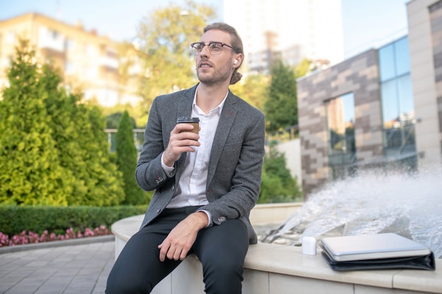 Uomo d'affari che beve caffè all'esterno dell'edificio