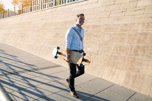 Uomo d'affari che cammina con lo skateboard