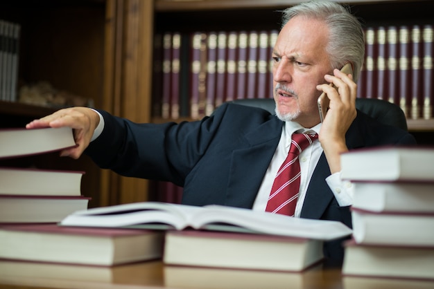 Uomo d&#39;affari che cattura un libro mentre parla al telefono