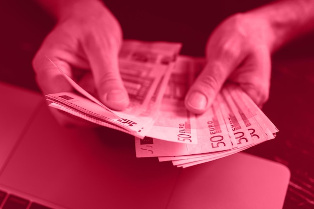 Uomo d'affari che conta soldi mani maschili ricche tiene e conta banconote in contanti da 50 euro banconote o banconote in valuta tonica nel colore di tendenza magenta viva dell'anno 2023