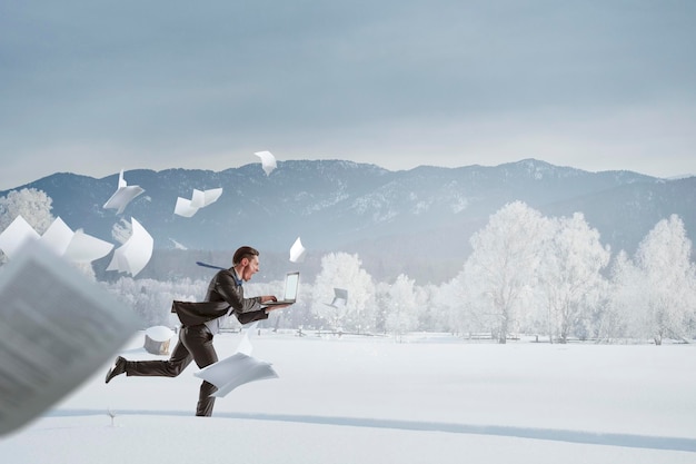 Uomo d'affari che corre tra la campagna della neve in inverno. Tecnica mista