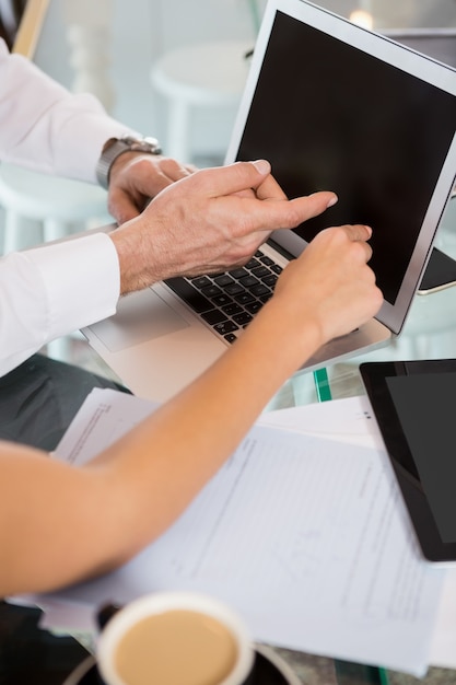 Uomo d'affari che discute con il collega che per mezzo del computer portatile