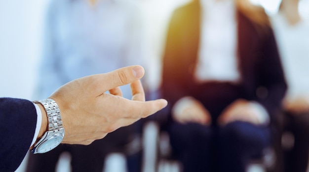 Uomo d'affari che fa presentazione a un gruppo di persone in ufficio. Relatore che tiene un seminario ai suoi colleghi. Concetto di lavoro di squadra e coaching.