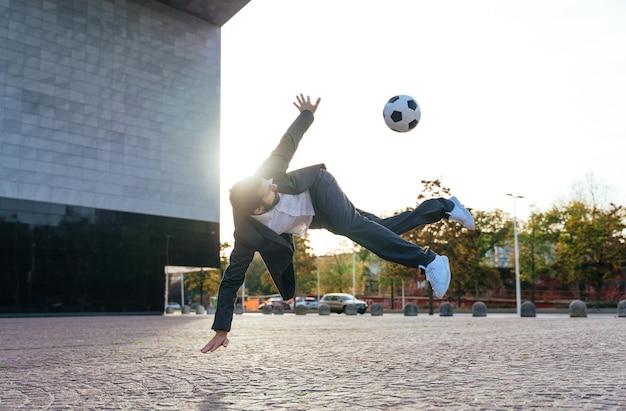 Uomo d'affari che gioca con un pallone da calcio e fa trucchi freestyle