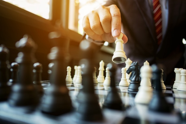 uomo d&#39;affari che gioca scacchi a bordo in ufficio, strategia e concetto di concorrenza