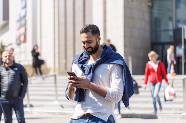 Uomo d'affari che guarda il suo telefono cellulare mentre si cammina per strada verso l'ufficio