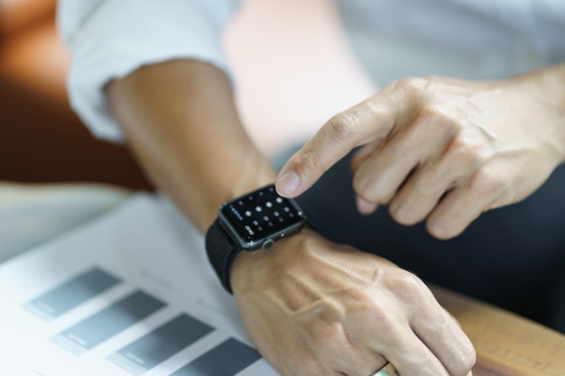 Uomo d'affari che guarda l'orologio intelligente In Office online collega la tecnologia Gadget