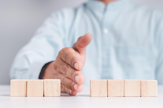 Uomo d'affari che indossa una camicia blu che dispone i blocchi di legno vuoti con le mani che è posizionato su un tavolo di legno bianco Strategia aziendale e piano d'azione Spazio di copia