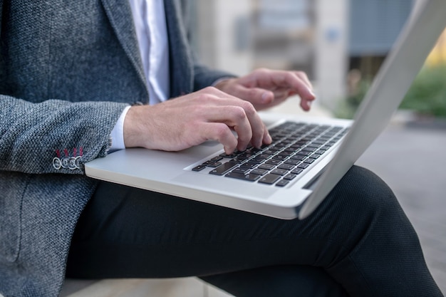 Uomo d'affari che lavora al computer portatile all'esterno dell'edificio