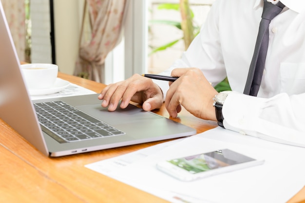 Uomo d&#39;affari che lavora al computer portatile con lavoro di ufficio sul tavolo