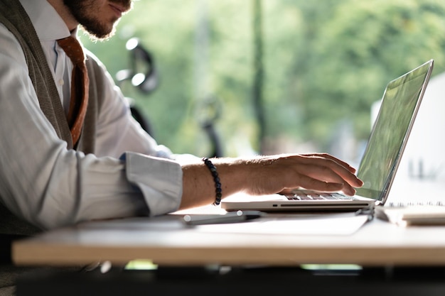 Uomo d'affari che lavora al computer portatile in ufficio moderno digitando sulla tastiera del computer portatile navigando in internet