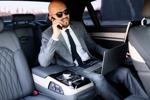 Uomo d'affari che lavora al computer portatile nel sedile posteriore dell'auto executive