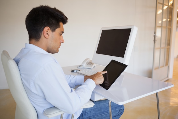 Uomo d&#39;affari che lavora al suo tablet al suo banco