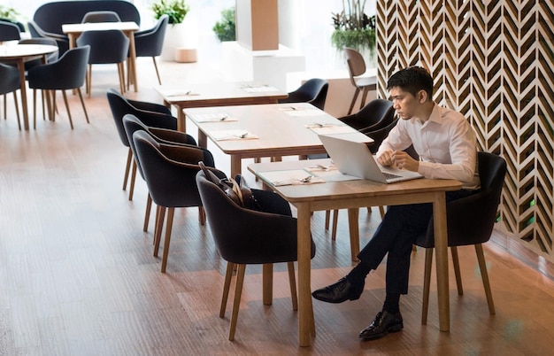 Uomo d'affari che lavora con il computer portatile al ristorante