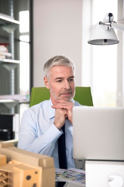 Uomo d'affari che lavora in ufficio, utilizzando il computer portatile