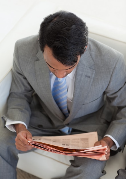 Uomo d&#39;affari che legge un giornale mentre aspettando un colloquio di lavoro