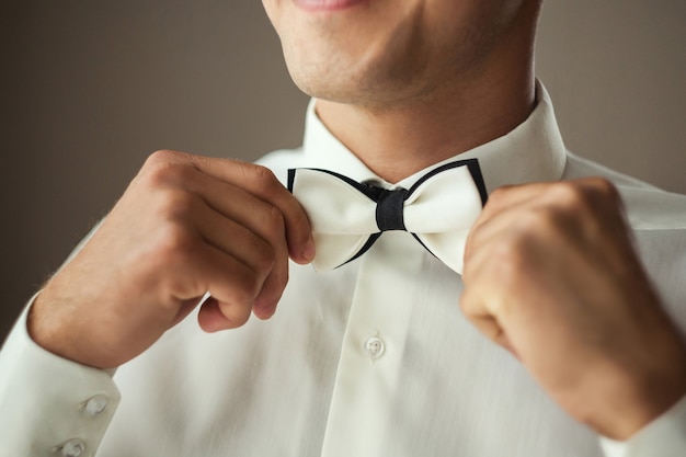 Uomo d'affari che mette sul farfallino, vestiti della farfalla dell'uomo, sposo che si prepara al mattino prima della cerimonia di nozze. Moda uomo