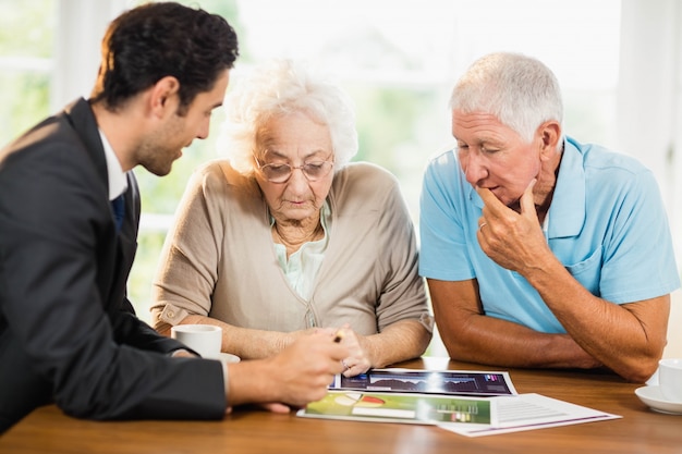 Uomo d'affari che mostra gli strati alle coppie senior a casa