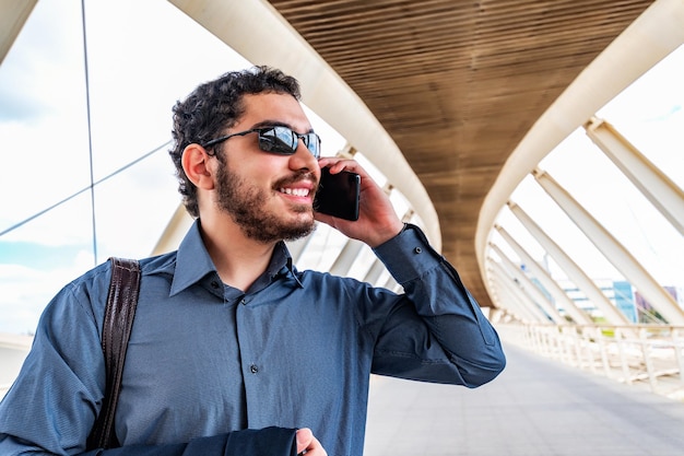 Uomo d'affari che parla al supporto all'aperto del telefono cellulare al ponte