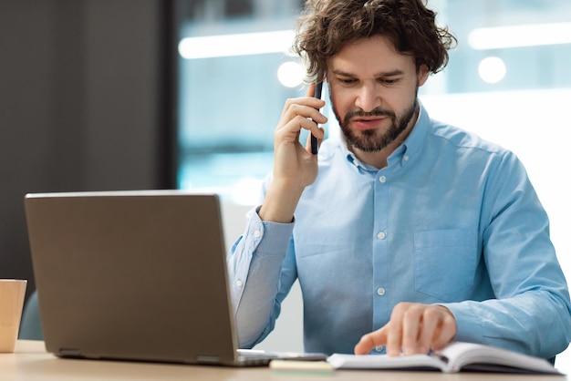 Uomo d'affari che parla al telefono al diario di lettura dell'ufficio