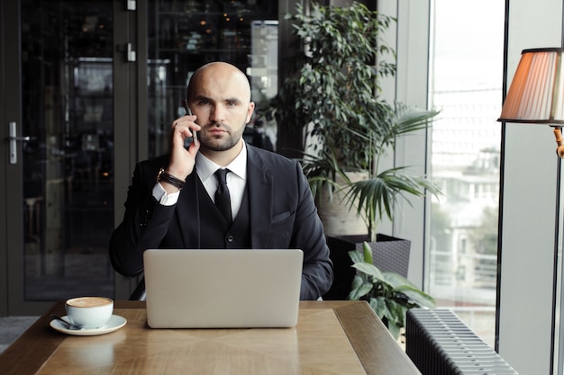 Uomo d'affari che parla al telefono in un caffè