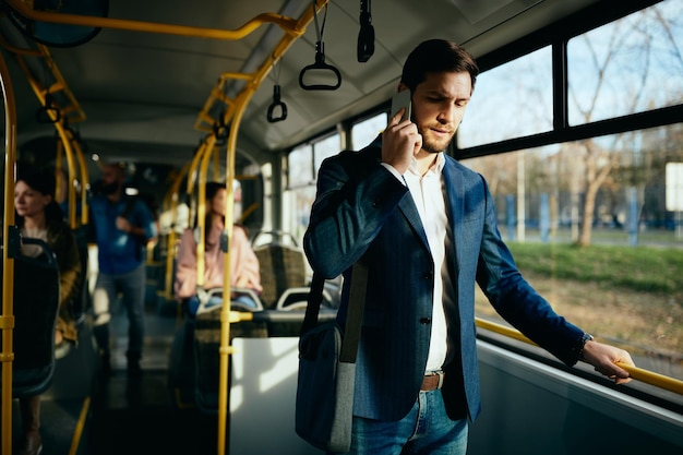 Uomo d'affari che parla al telefono mentre si reca al lavoro in autobus