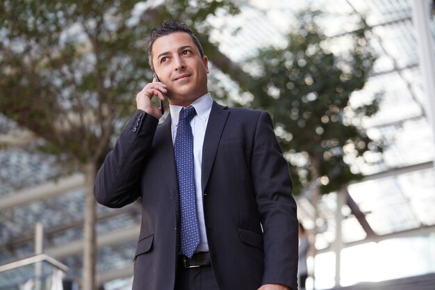 Uomo d'affari che parla con cellulare nell'ambiente urbano