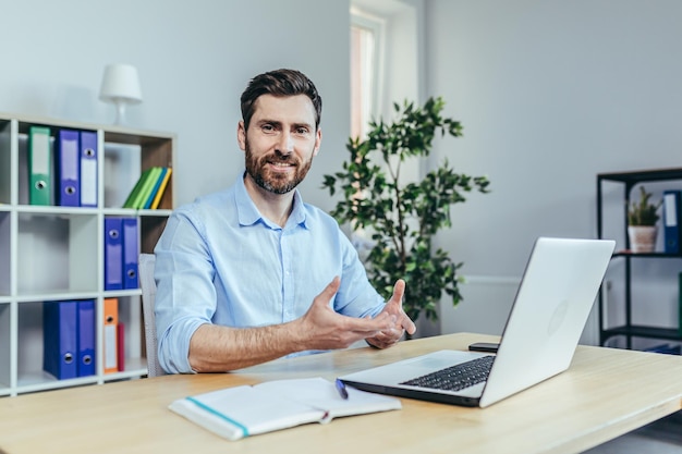 Uomo d'affari che parla su laptop webcam videochiama uomo al lavoro guardando la fotocamera e sorridente dipendente di successo