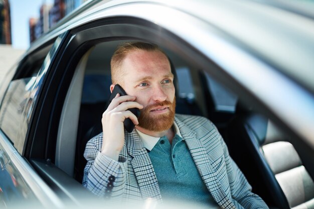 Uomo d'affari che parla sul telefono in automobile