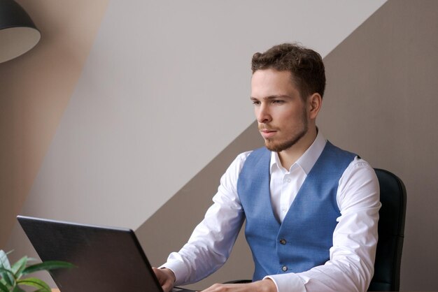 Uomo d'affari che pensa al progetto online guardando il laptop sul posto di lavoro