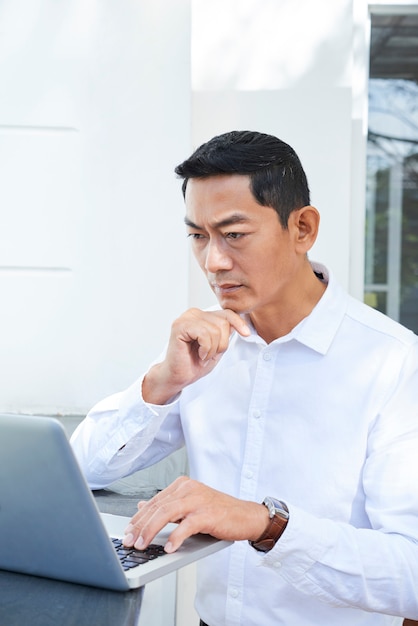 Uomo d'affari che per mezzo del computer portatile