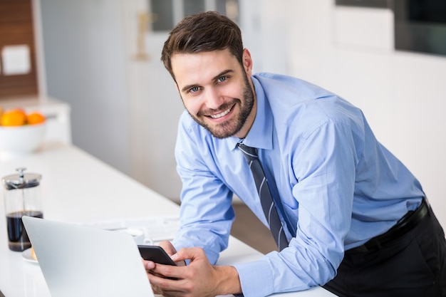 Uomo d'affari che per mezzo del telefono cellulare a casa