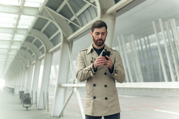 Uomo d'affari che per mezzo dello smartphone mentre camminando