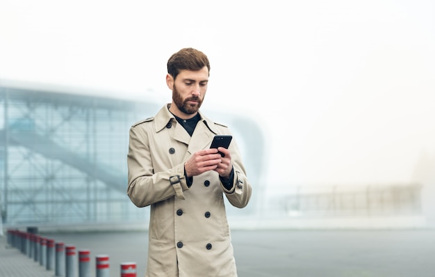 Uomo d'affari che per mezzo dello smartphone mentre camminando