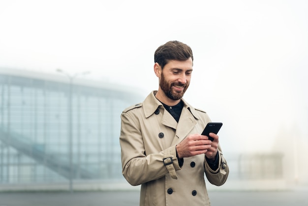 Uomo d'affari che per mezzo dello smartphone mentre camminando