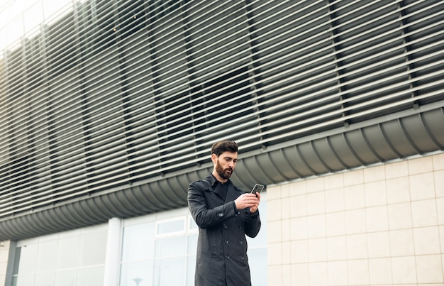 Uomo d'affari che per mezzo dello smartphone mentre camminando