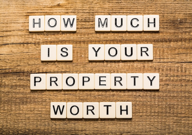 Uomo d'affari che punta alla lavagna trasparente con il testo: quanto vale la tua proprietà?