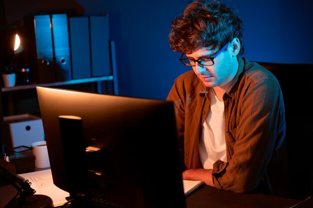 Uomo d'affari che si concentra sul computer su un progetto presso l'ufficio di luce al neon Gusher
