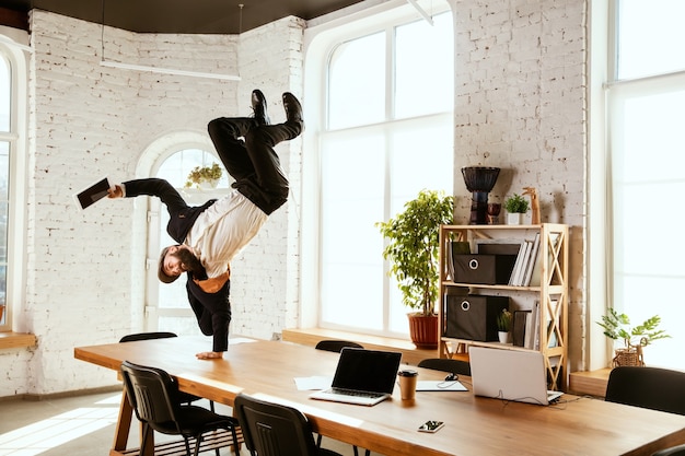 Uomo d'affari che si diverte a ballare break dance in ufficio al lavoro