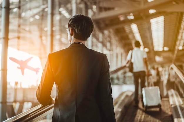 Uomo d'affari che si trasferisce al gate del terminal per il check-in, imbarco con i bagagli in aeroporto per un viaggio d'affari.