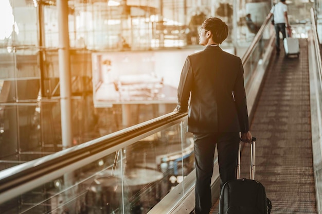 Uomo d'affari che si trasferisce al gate del terminal per il check-in, imbarco con i bagagli in aeroporto per un viaggio d'affari.