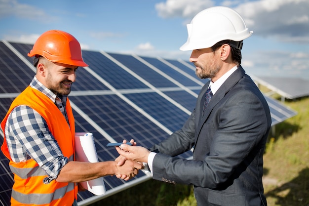 Uomo d&#39;affari che tiene dettaglio fotovoltaico e che stringe la mano a un caporeparto.