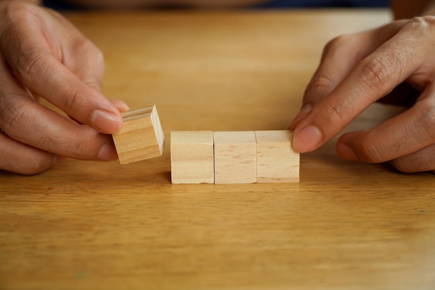 Uomo d'affari che tiene due blocchi di legno disposti in filaMani disposti blocchi di legno impilati come gradini