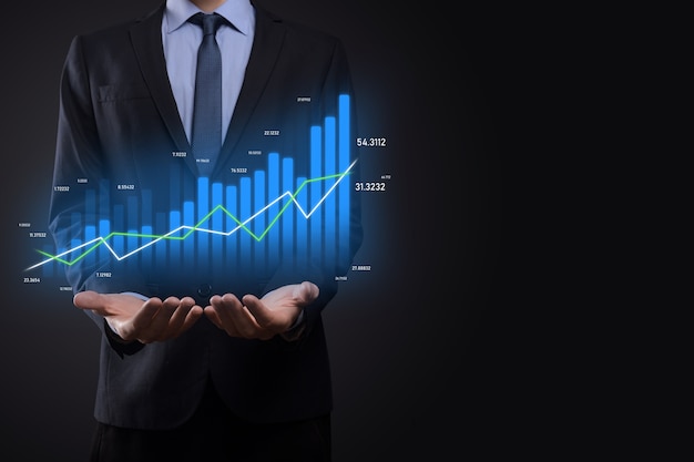 Uomo d'affari che tiene grafici olografici e statistiche del mercato azionario guadagna profitti