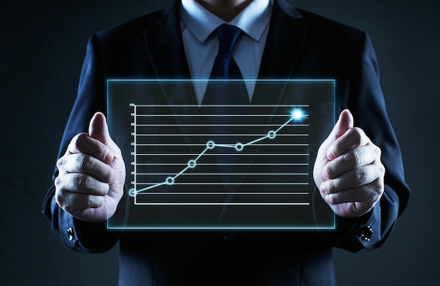 Uomo d'affari che tiene un vetro dello schermo con il grafico dello stato finanziario, concetto ideale di crescita aziendale.