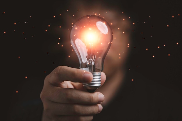 Uomo d'affari che tiene una lampadina incandescente all'idea creativa di pensiero intelligente per il concetto di ispirazione e innovazione