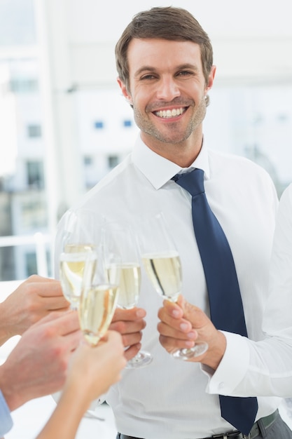 Uomo d&#39;affari che tosta con champagne in ufficio