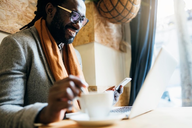 Uomo d'affari che usa il cellulare al caffè