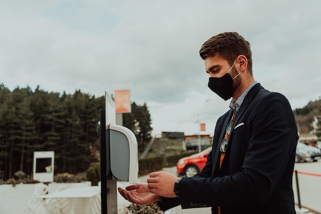 Uomo d'affari che usa un dispenser di gel igienizzante per le mani che adotta per prevenire la diffusione del coronavirus