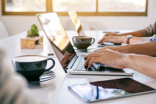 Uomo d'affari che utilizza e lavora al computer portatile con un tablet pc sul tavolo in ufficio